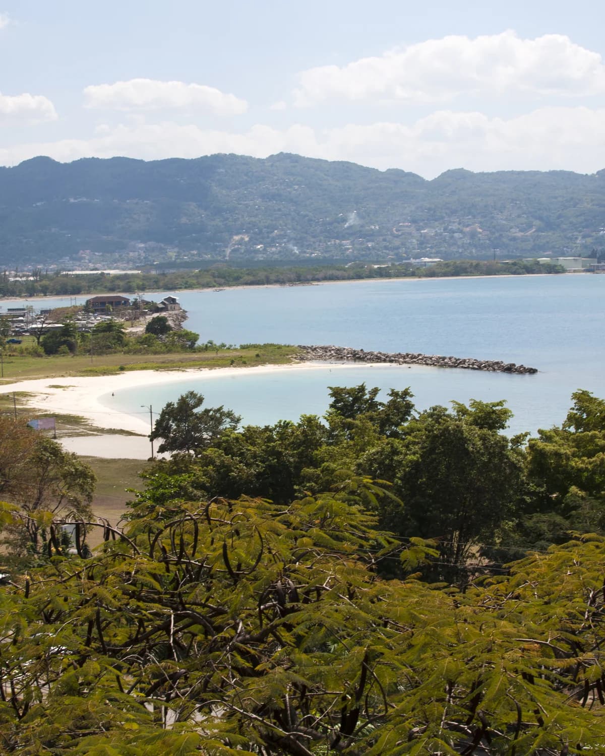 Montego Bay from the hills above it, looking down over a curved beach, the harbour and the town against green mountains